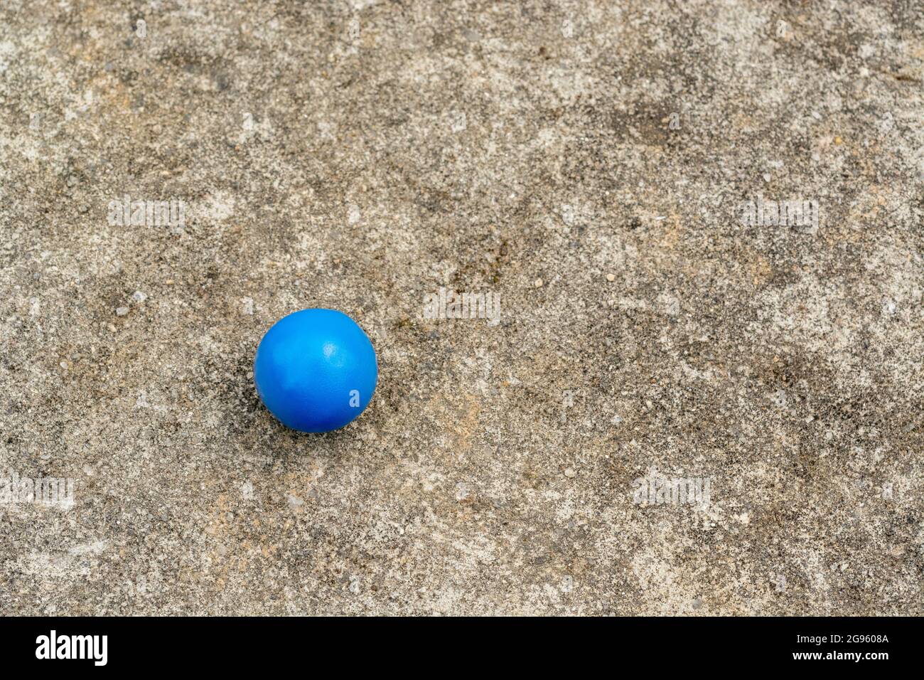 Sphère en plastique bleu sur la surface de ciment abîmé + espace de copie. Pour « tout seul », isolement, singulier, boule bleue, balle dans votre cour, solitude abstraite Banque D'Images