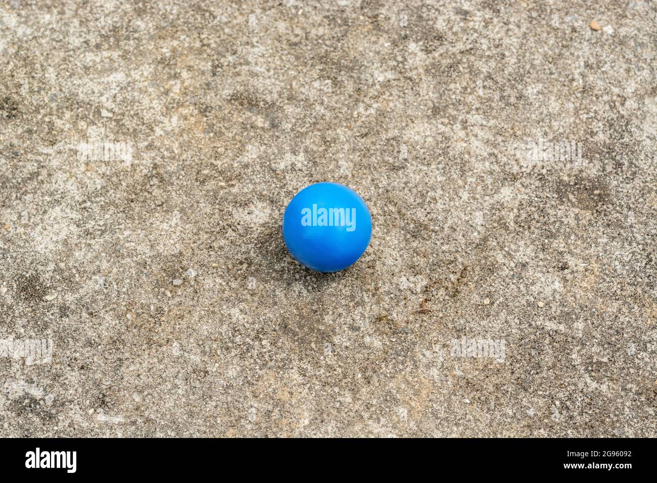 Sphère en plastique bleu sur la surface de ciment abîmé + espace de copie. Pour « tout seul », isolement, singulier, boule bleue, balle dans votre cour, solitude abstraite Banque D'Images