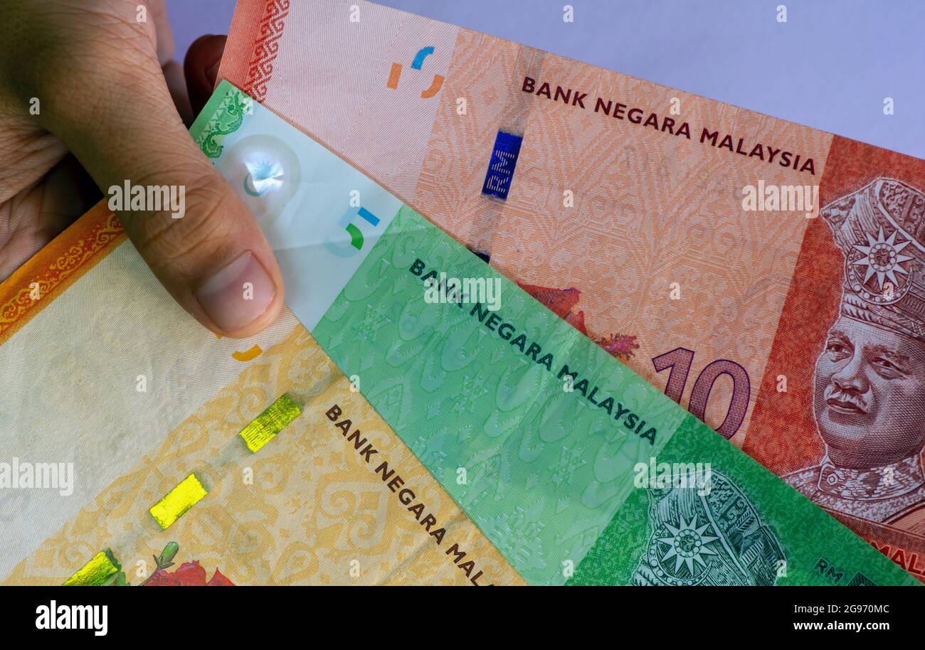 Main d'enfant asiatique tenant l'argent de Ringgit Malaysia, dans peu de focus. Banque D'Images