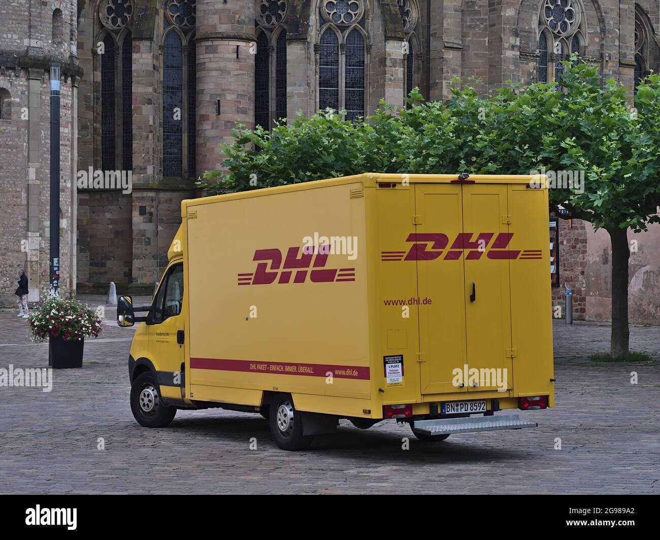 Minibus de livraison de couleur jaune du transporteur DHL (faisant partie du groupe Deutsche Post DHL) avec parking rouge de la société sur la place Domfreihof au centre de Trèves. Banque D'Images