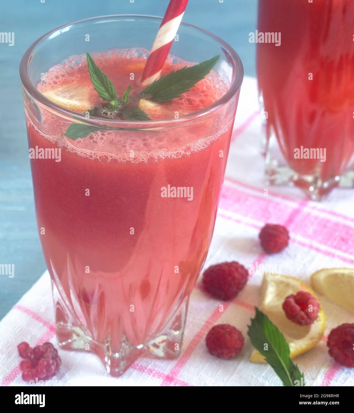 Jus de pastèque dans un verre avec citron et framboises. Banque D'Images