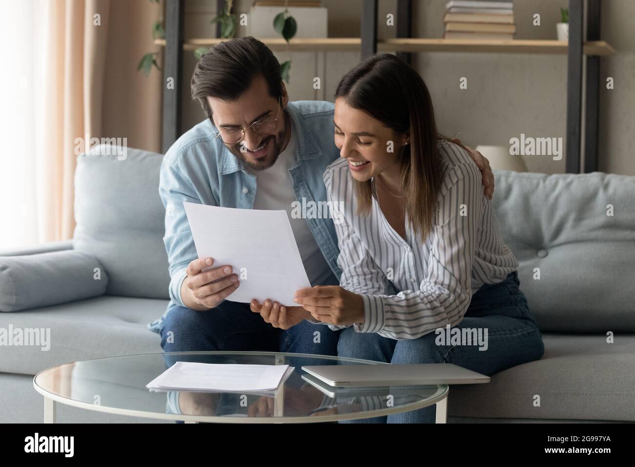 Un couple souriant s'assoit sur un canapé pour lire a reçu une lettre formelle Banque D'Images