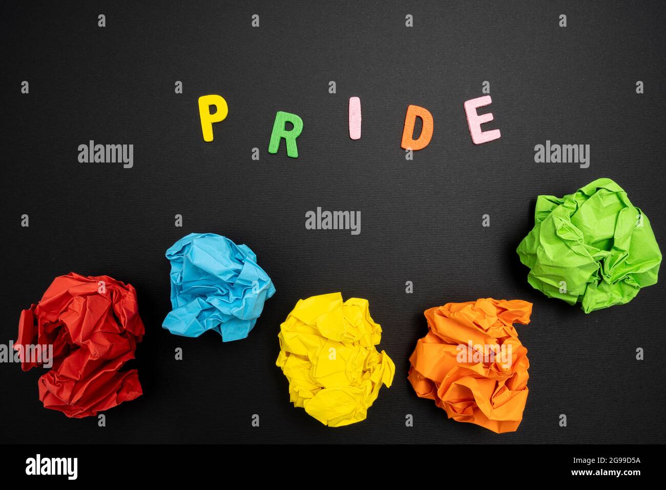 Quelques feuilles de papier couleur froissé et le mot Pride sur une surface noire Banque D'Images