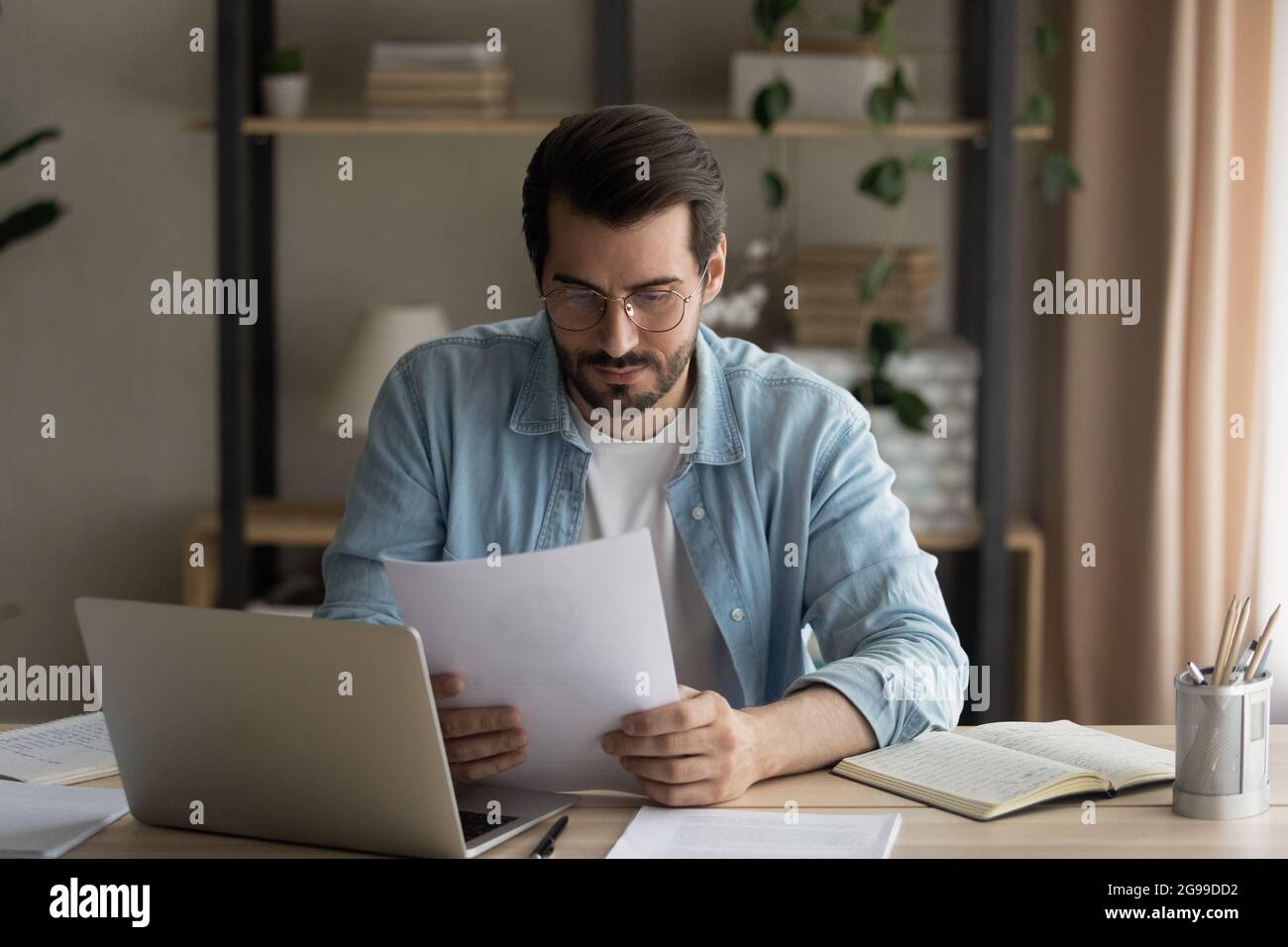 Un homme d'affaires sérieux lisant un contrat assis au bureau du lieu de travail Banque D'Images