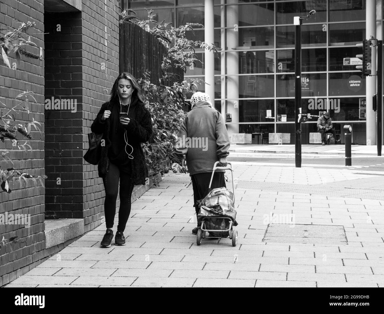 Fille au téléphone et Old Lady avec chariot de shopping, Newcastle upon Tyne Banque D'Images