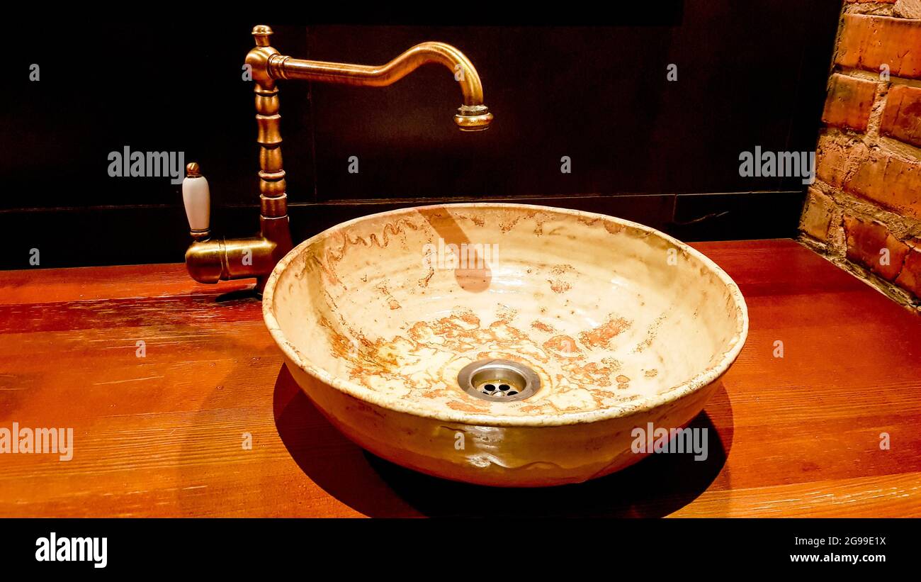 Un joli robinet vintage et un mélangeur doré tapoter sur un lavabo rond en marbre dans la salle de bains. Intérieur d'une toilette chère avec un lavabo en marbre. Banque D'Images