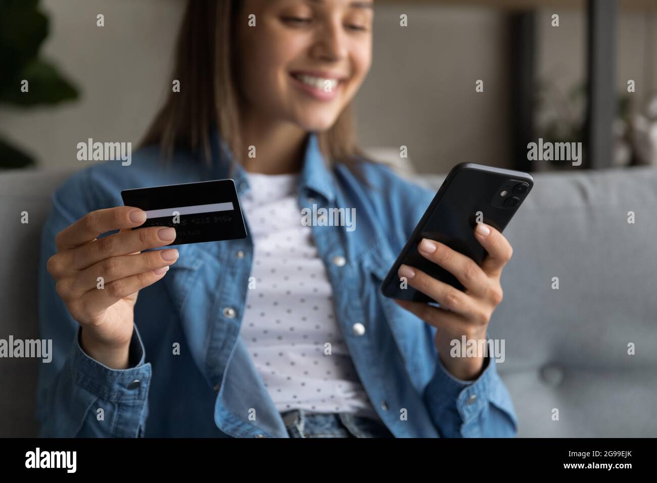 Une femme qui détient une carte de crédit et un smartphone bénéficie de services d'achat en ligne Banque D'Images