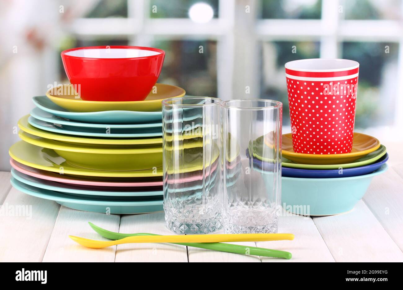 Vaisselle colorée sur table en bois sur fond de fenêtre Photo Stock - Alamy
