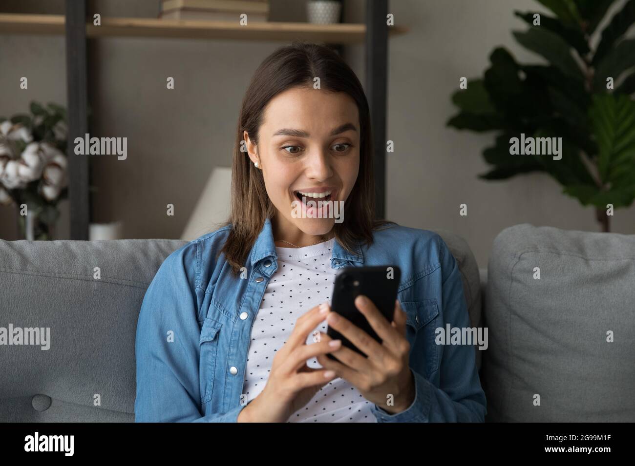 Une femme a lu les nouvelles des médias sur son téléphone portable semble stupéfait Banque D'Images
