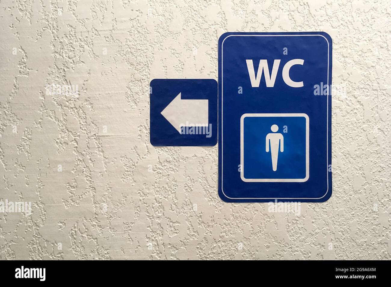 Flèche, pointeur sur la plaque bleue de la toilette publique mâle signб sur  le mur en plâtré. Panneau de toilettes. Toilettes concept .WC. Tir  horizontal. Copier l'espace. Gros plan Photo Stock -