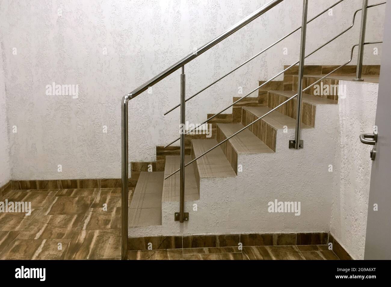 Escaliers depuis les carreaux à côté du mur en plâtré dans un bâtiment moderne industriel. Escalier avec mains courantes de style industriel. Copier l'espace. Gros plan. Indo Banque D'Images