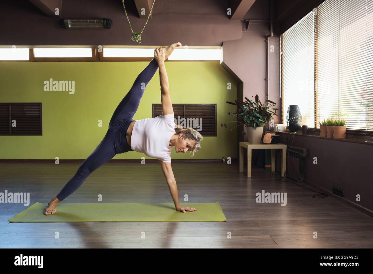 Une femme menant un mode de vie sain, faisant du yoga, exécute en studio l'exercice vasishthasana, la pose de la sauge Banque D'Images