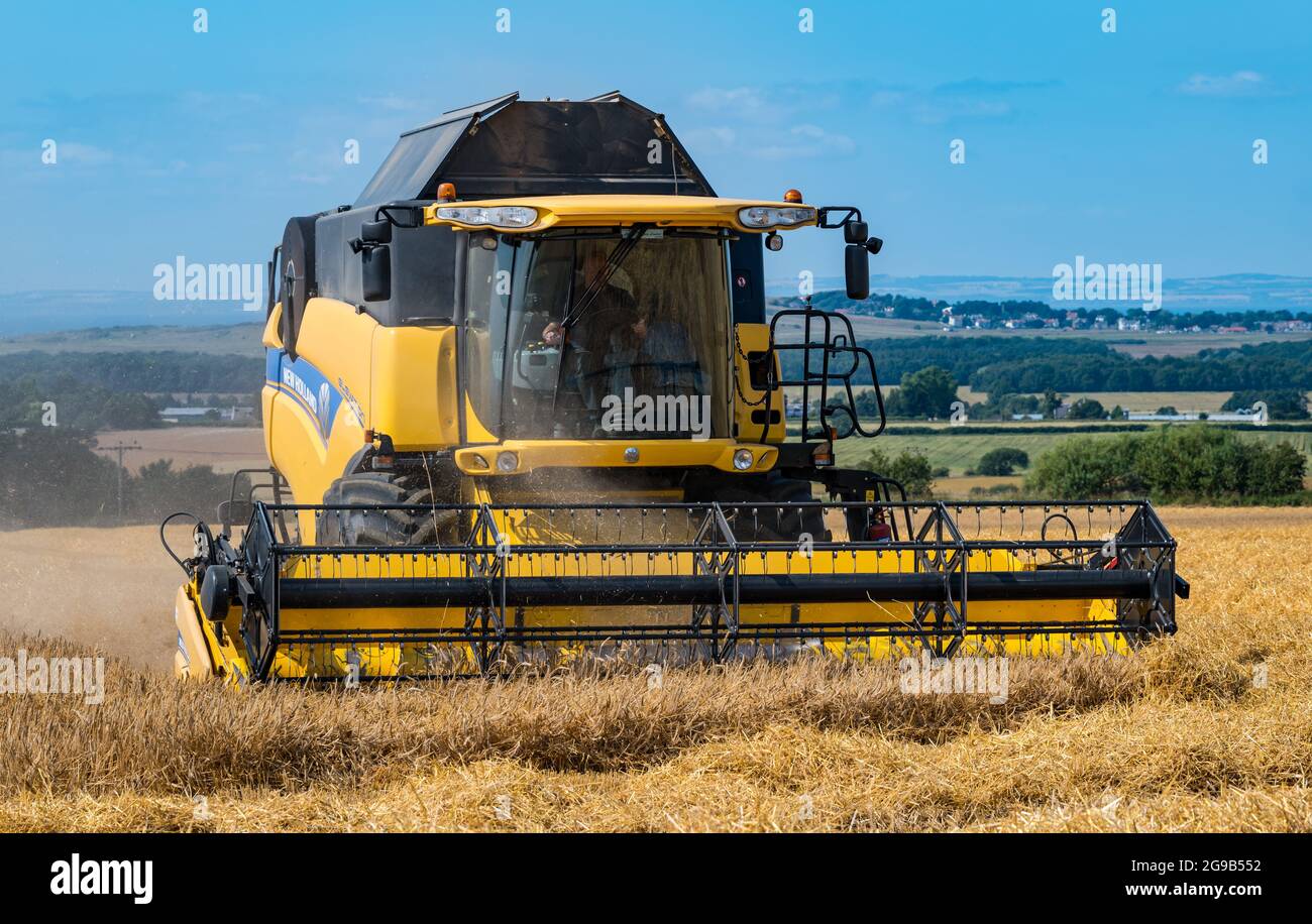 Byres Farm, East Lothian, Écosse, Royaume-Uni, 25 juillet 2021. Météo au Royaume-Uni: Récolte d'orge d'hiver: Le récent temps sec a permis à un agriculteur de commencer tôt la récolte. Photo : une moissonneuse-batteuse New Holland au travail Banque D'Images