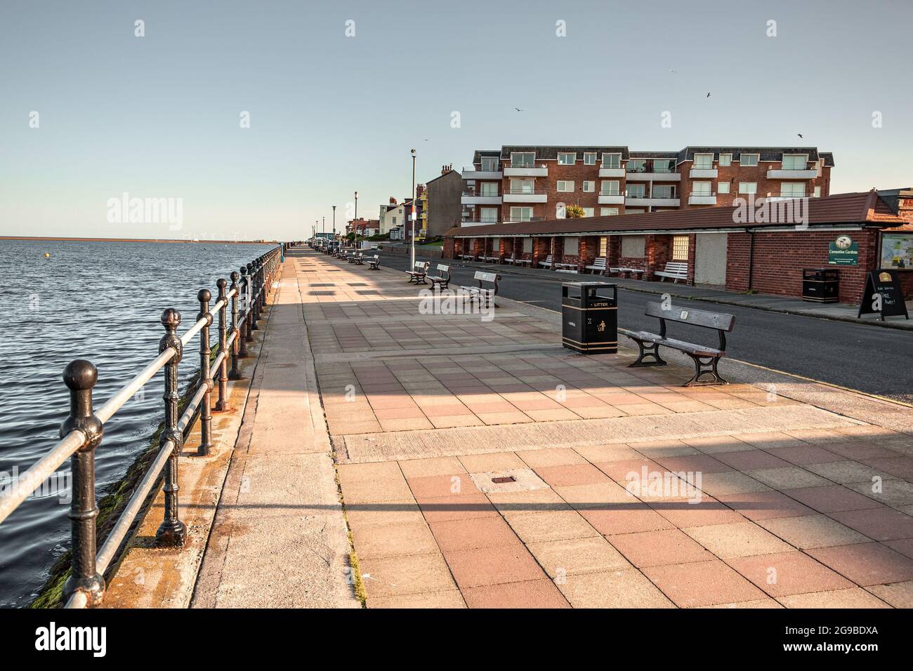West Kirby, Wirral, Royaume-Uni. Promenade le long du lac marin, South Parade. Soleil tôt le matin et longues ombres. Banque D'Images