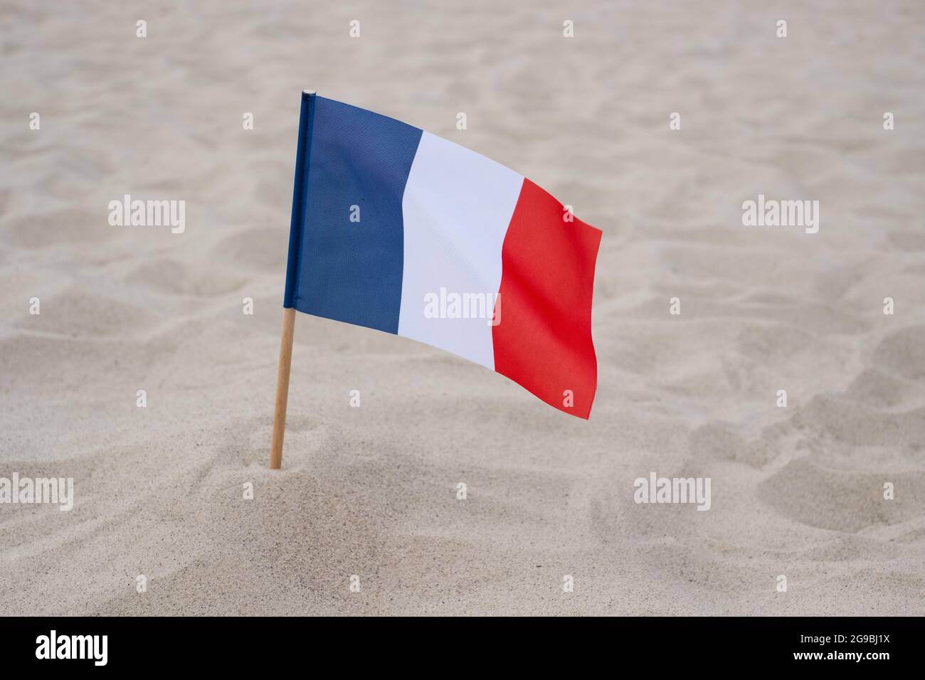 Drapeau de la France sur fond de sable. Drapeau français agitant dans le vent sur la plage d'été Banque D'Images