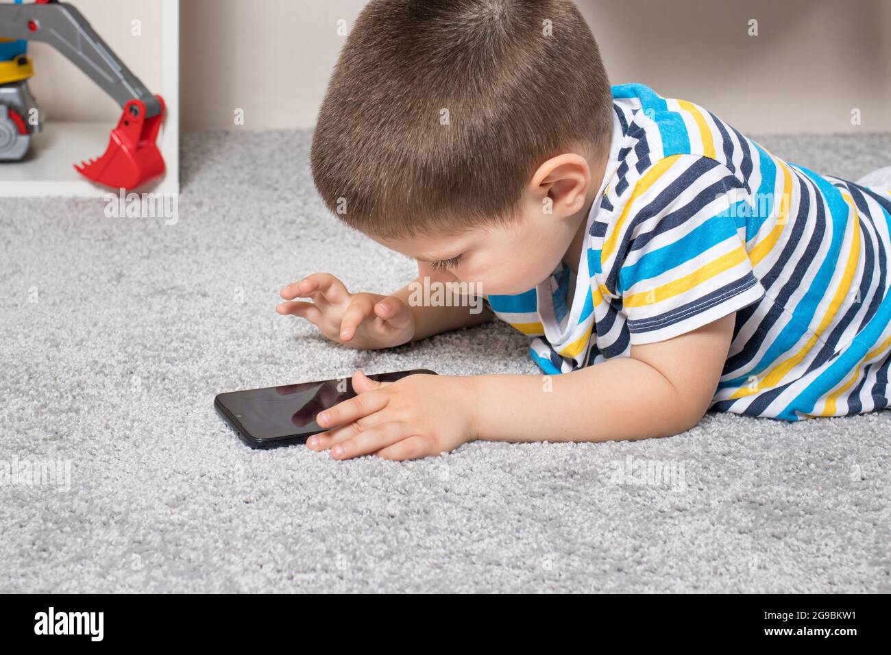Un petit garçon de 3-4 ans regarde l'écran du téléphone. Dessins