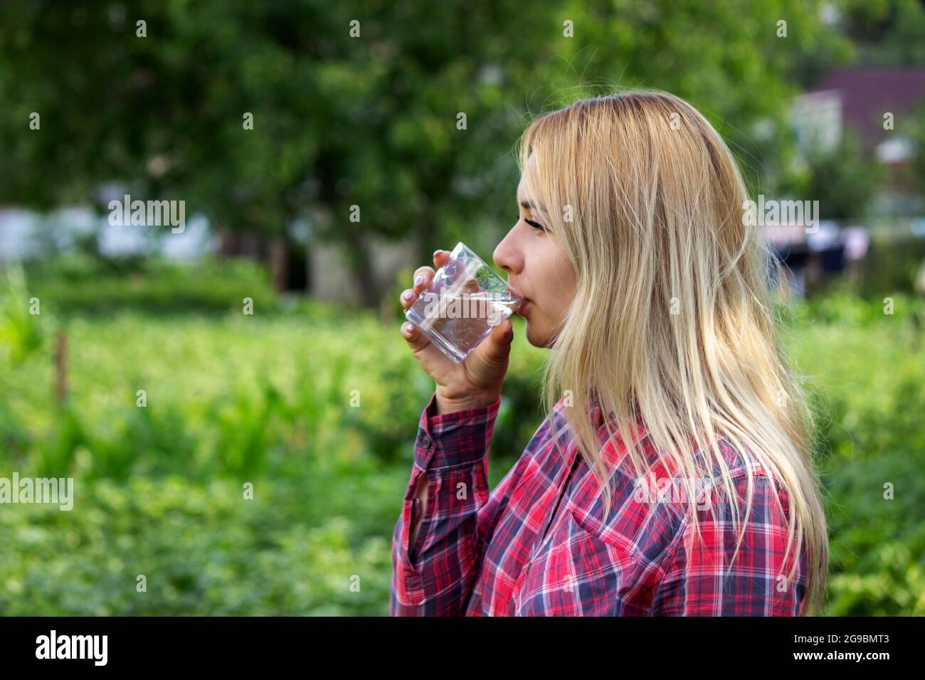 une fille boit de l'eau depuis un verre, à l'extérieur. Mise au point sélective Banque D'Images