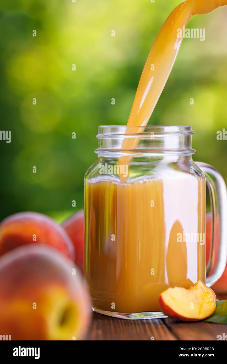 jus de pêche frais versé dans un pot de maçon à l'extérieur Banque D'Images jus de pêche frais versé dans un pot de maçon à l'extérieur Banque D'Images
