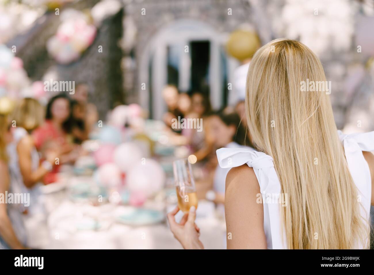 Verre de champagne à la main pour fille sur le fond d'une table servie avec les invités Banque D'Images