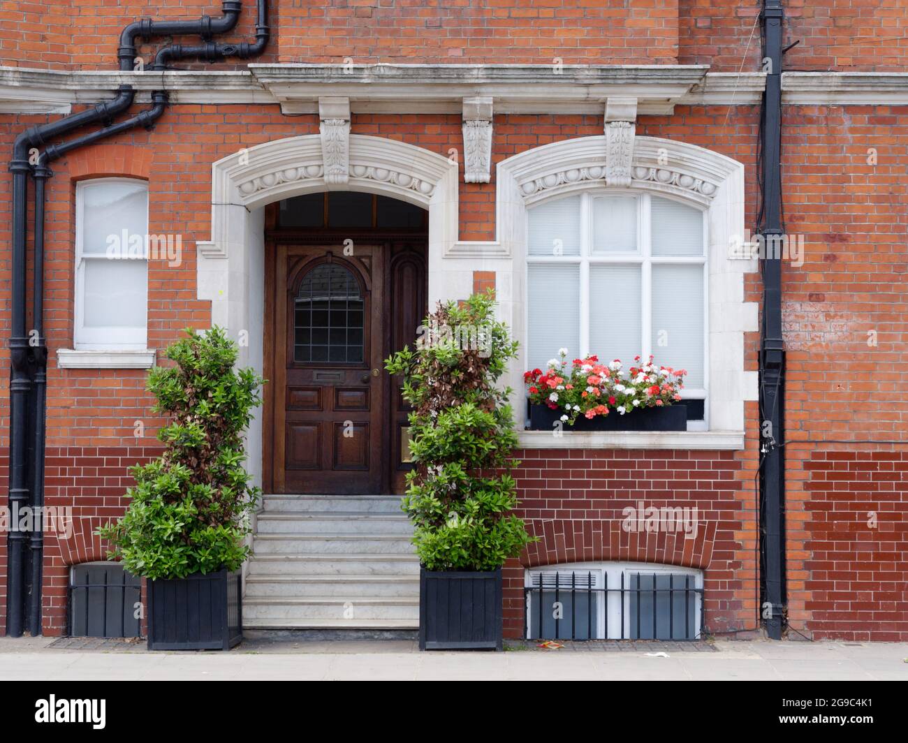 Londres, Grand Londres, Angleterre, 12 juin 2021: Propriété résidentielle en brique avec un escalier menant à une porte d'entrée marron. Banque D'Images