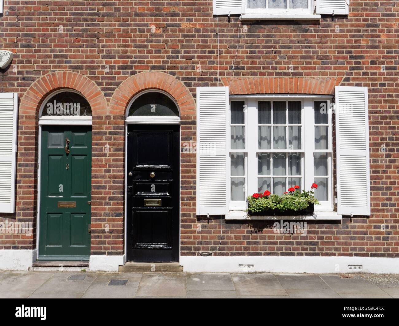 Londres, Grand Londres, Angleterre, juin 12 2021 : portes avant vertes et noires de propriétés résidentielles avec une boîte de fenêtre pleine de plantes et de fleurs. Banque D'Images