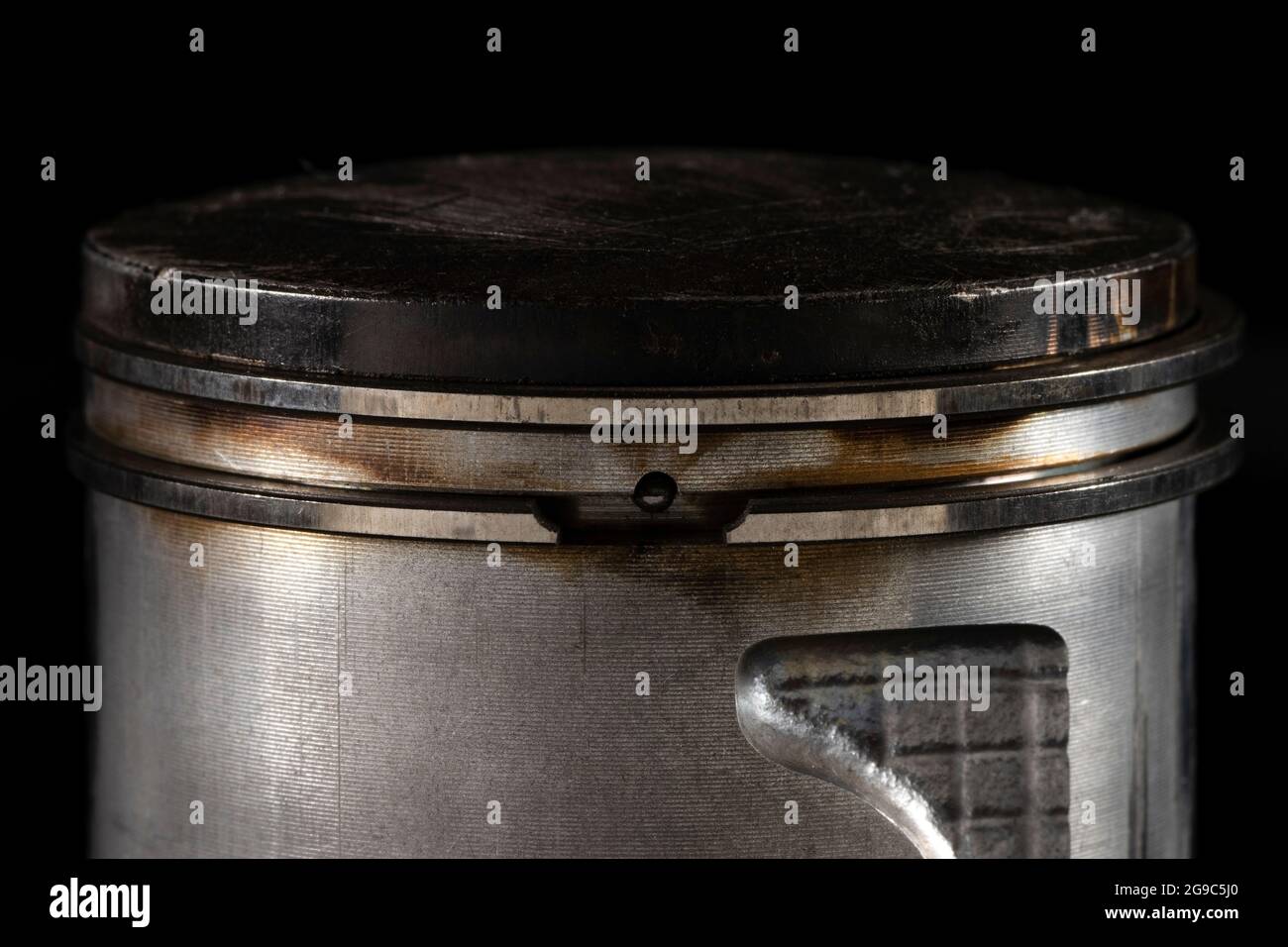 Ancien piston du moteur cassé isolé sur fond noir Banque D'Images