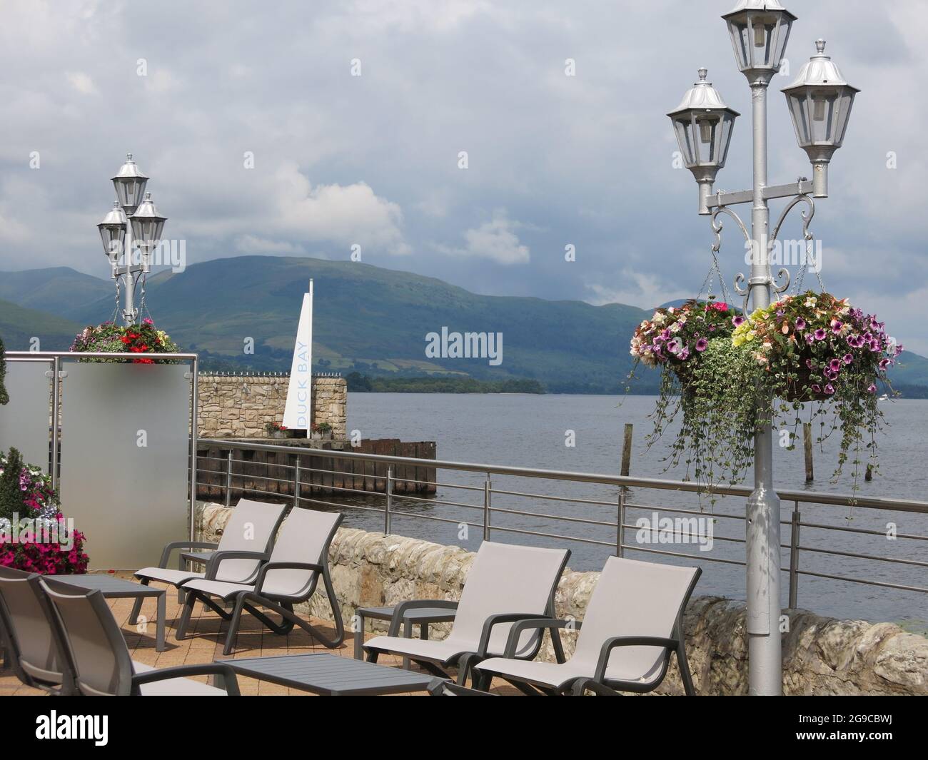 Vue panoramique sur le Loch Lomond depuis le restaurant de Duck Bay Marina, avec paniers suspendus le long de la terrasse au bord de l'eau. Banque D'Images