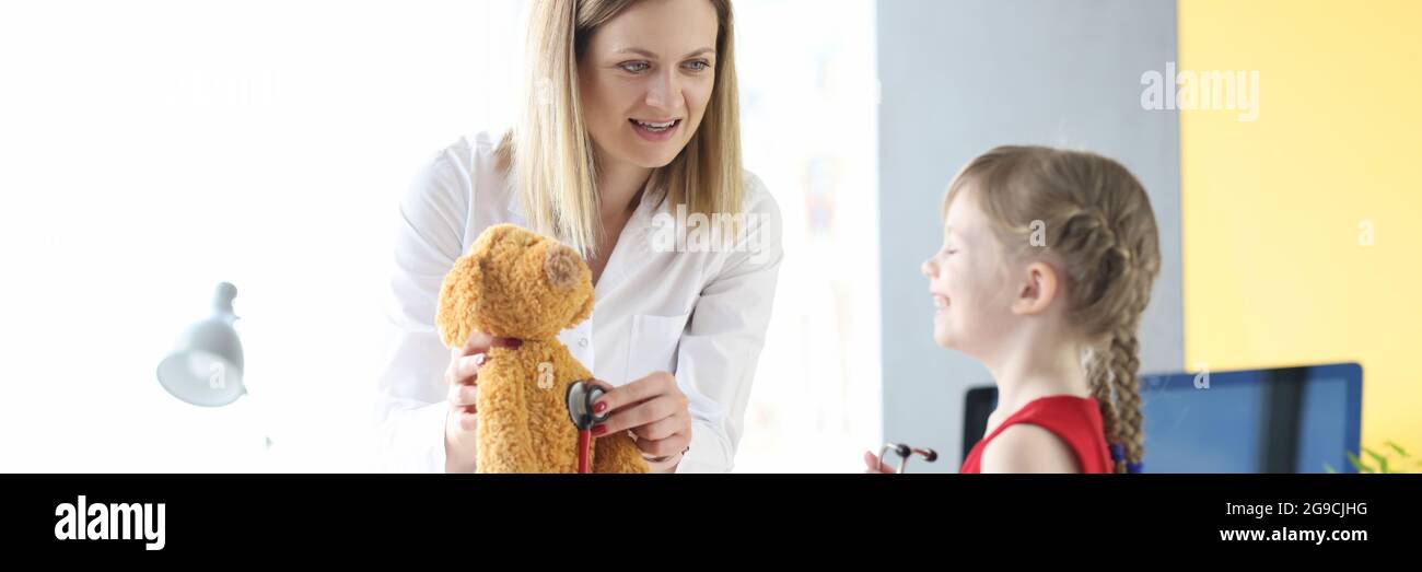 Petite fille à l'écoute de l'ours jouet avec stéthoscope avec médecin Banque D'Images