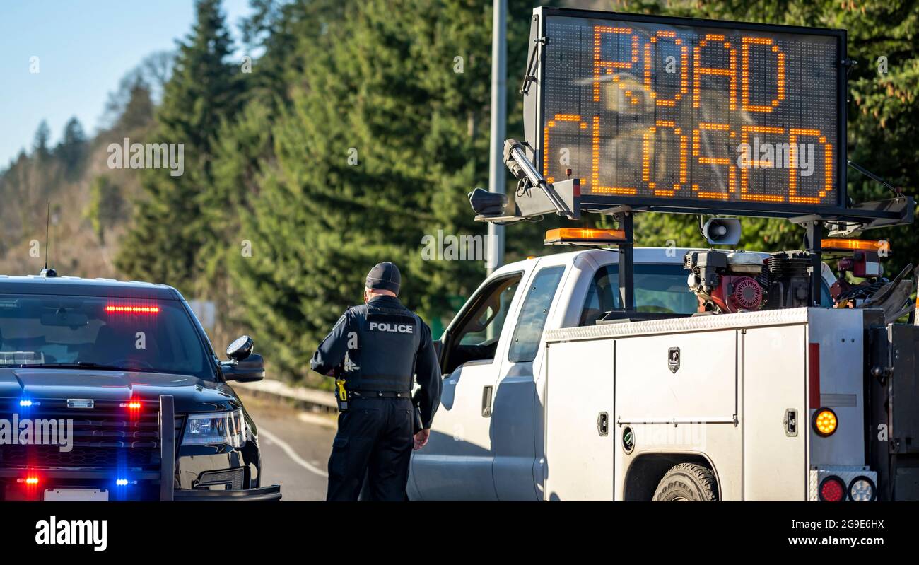 Officier de police en tenue et uniforme sur une voiture de police avec des feux clignotants et une voiture de service de route avec une carte électronique avec la route d'inscription est c Banque D'Images