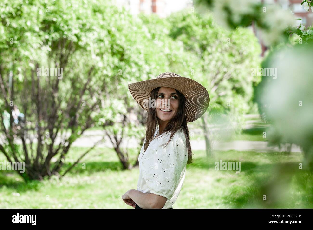 Portrait jolie et attrayante femme dans un chapeau de paille. Jeune femme sur fond de parc de printemps. Mignonne souriante et heureuse jeune femme. Magnifique modèle o Banque D'Images