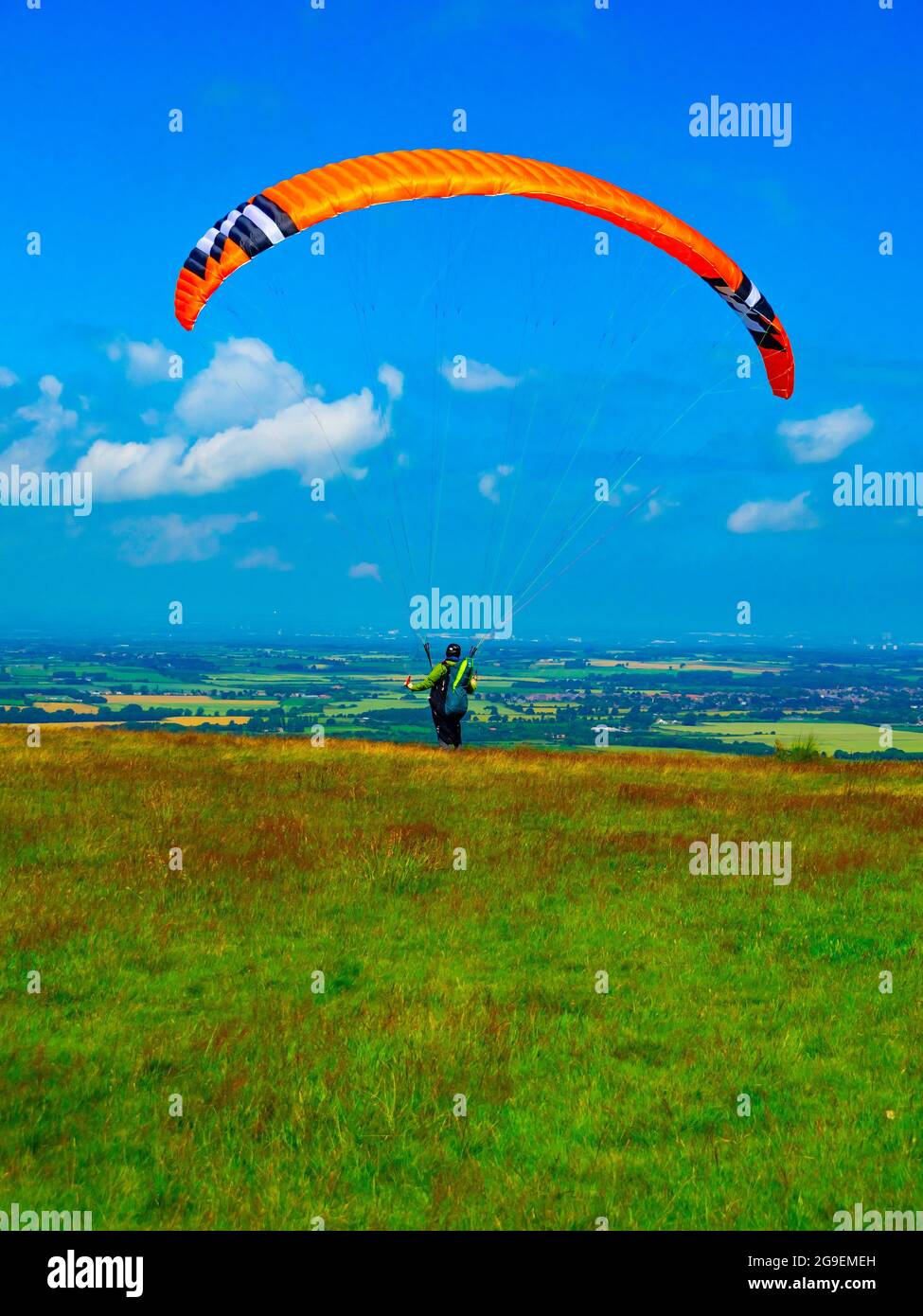 Un homme avec un parachute ascensionnel orange qui tente de se départir dans un vent trop faible sur les landes du yorkshire Banque D'Images