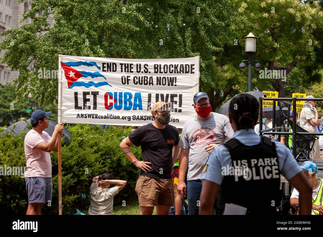 Washington, DC, Etats-Unis, 25 juillet 2021. Sur la photo : les manifestants portent un panneau appelant les États-Unis à « laisser Cuba vivre », tandis qu'ils sont surveillés par un agent de la police du parc chargé des séparer des démostrateurs pro-intervention concurrents SOS Cuba qui tiennent leur propre rassemblement à la Maison Blanche. Le rassemblement Let Cuba Live a appelé à la fin du blocus américain de Cuba et a célébré l'arrivée des marcheurs Puentes de Amor (ponts d'amour) à la fin de leur voyage de 1300 miles de Miami à DC pour protester contre le blocus américain de l'île. Les marcheurs ont également apporté une pétition contenant près de 30,000 signatures Banque D'Images