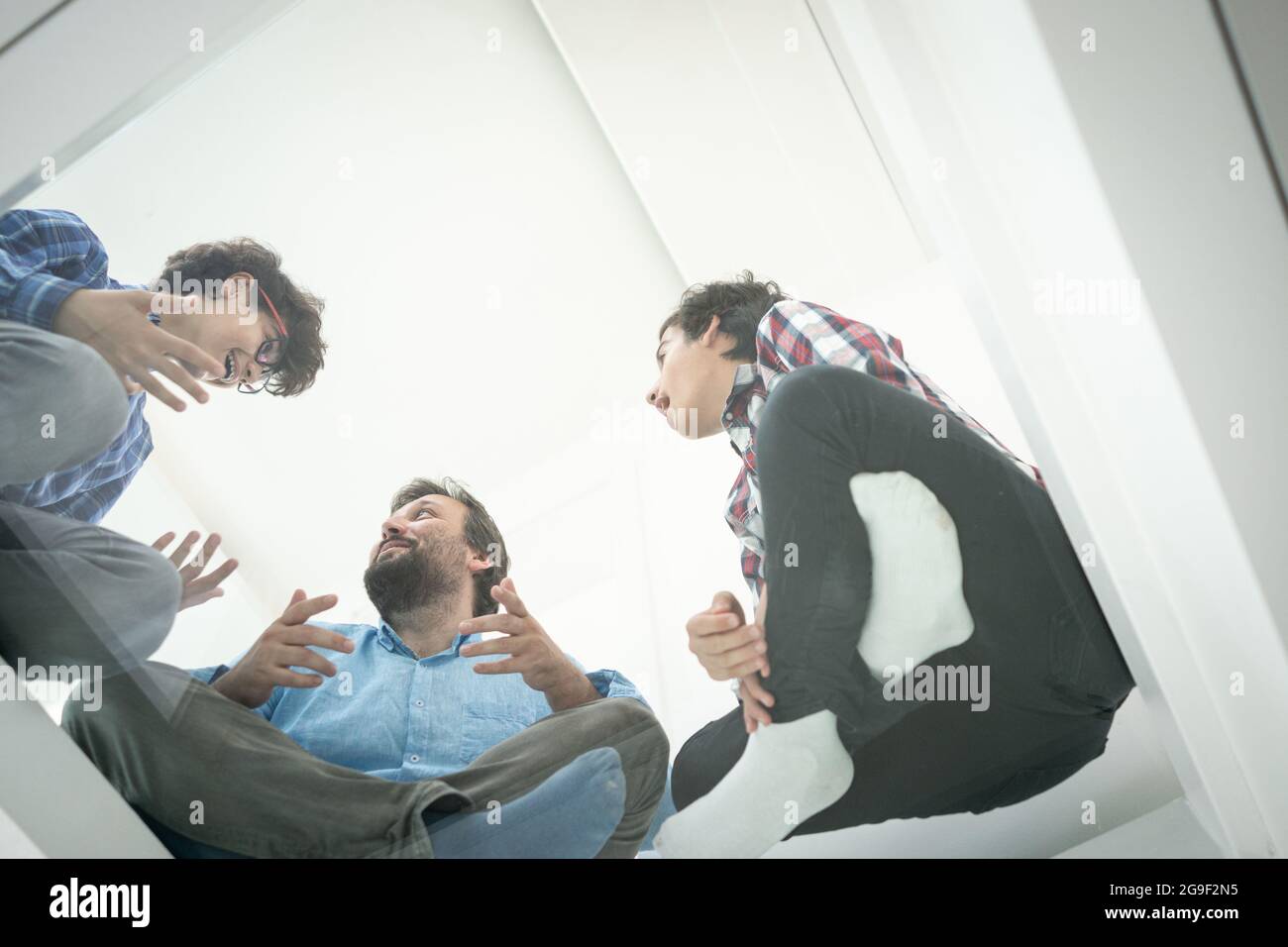 Angle bas du père et des fils assis sur le verre Banque D'Images