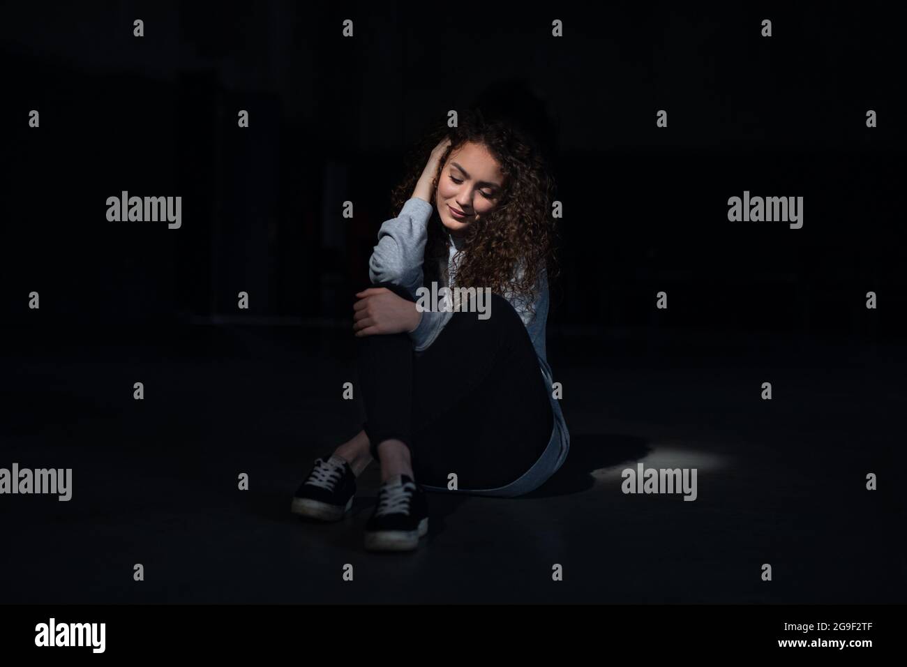 Portrait d'une jeune femme heureuse assise à l'intérieur contre un germon noir. Banque D'Images