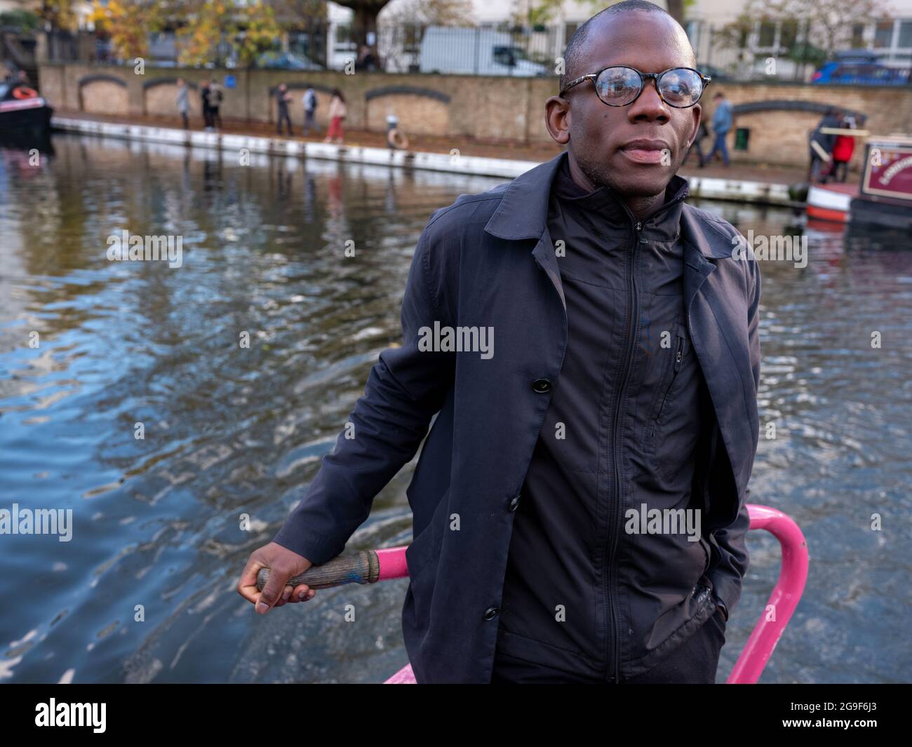 Un homme noir qui dirige un bateau étroit avec un timon le long du canal Regent's à Little Venice, Londres. Banque D'Images