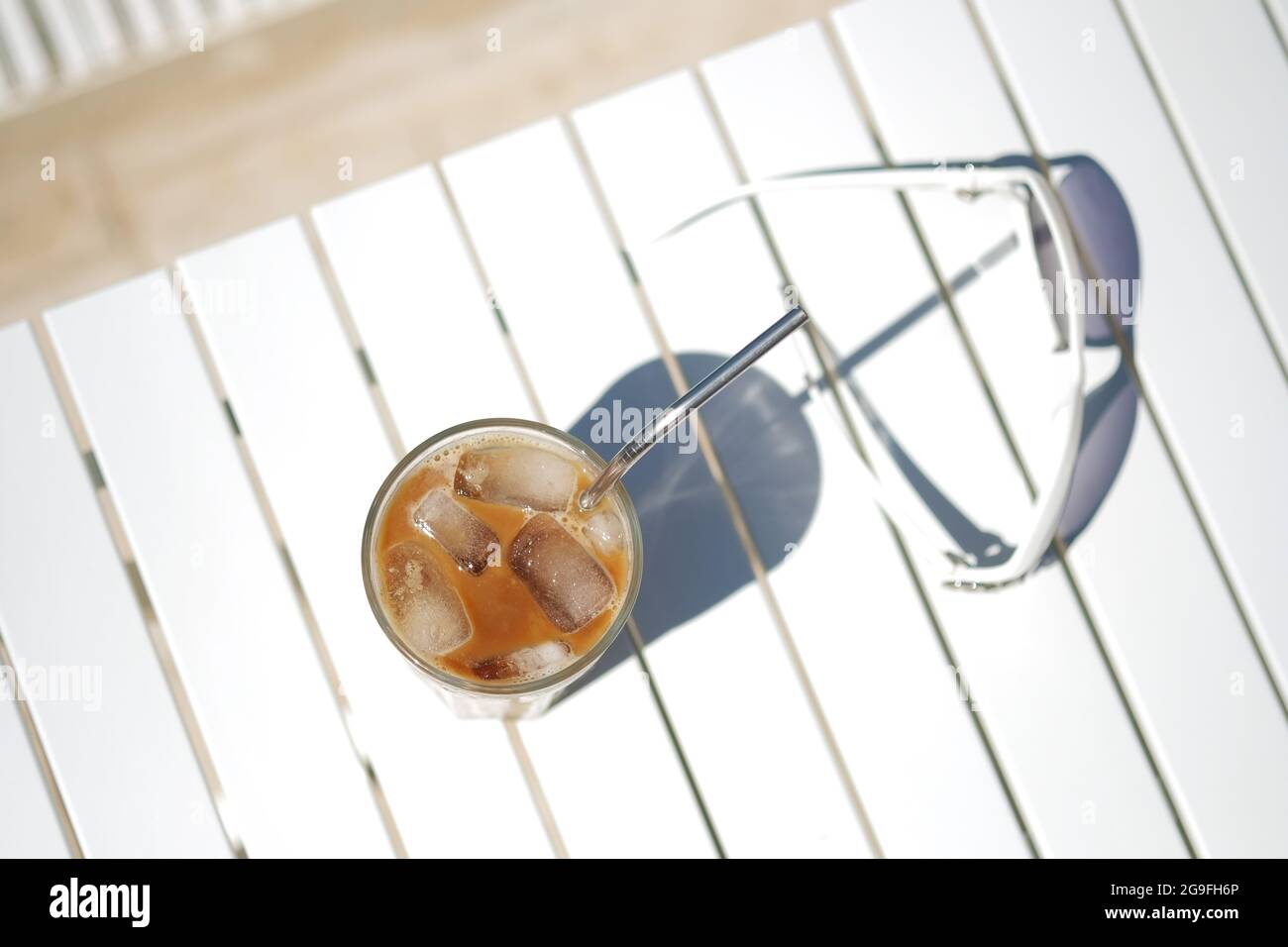 Café glacé Cyprus Frappe Fredo vue de dessus sur table blanche, avec lunettes de soleil. Arrière-plan, vacances ou concept de vacances minimalistes d'été. Soleil et ombres. Banque D'Images