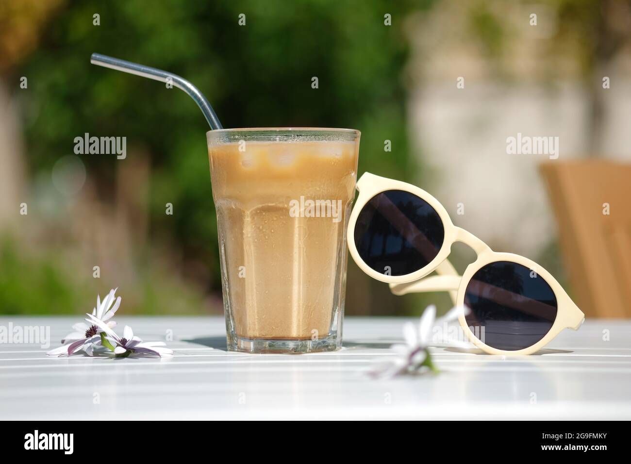 Café glacé Cyprus Frappe Fredo vue latérale sur table blanche, avec lunettes de soleil. Arrière-plan, vacances ou concept de vacances minimalistes d'été. Soleil et ombres Banque D'Images
