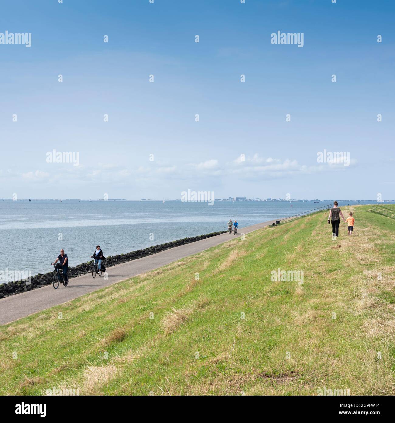 en été, les gens marchent à vélo sur la digue près d'oudeschild, sur l'île hollandaise de texel, sous le ciel bleu Banque D'Images