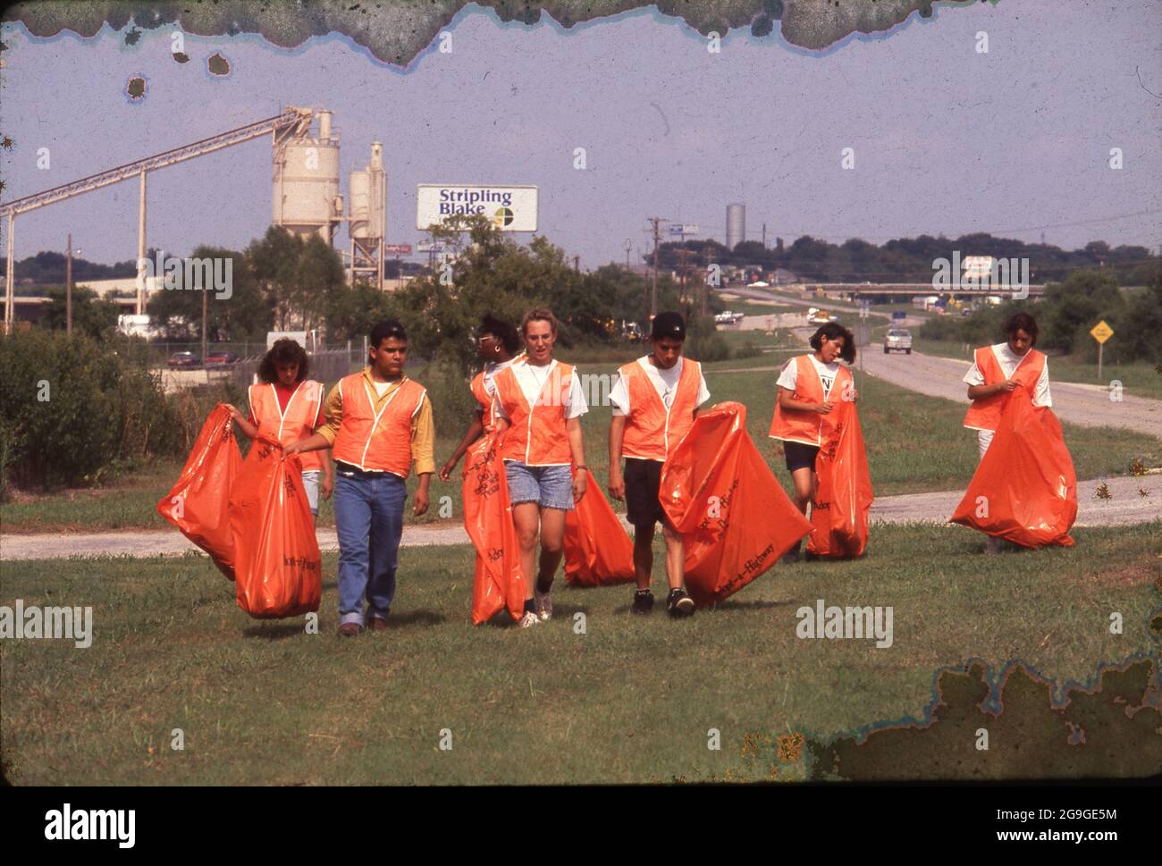 New Braunfels Texas USA: Les adolescents volontaires portent des gilets réfléchissants orange vif tout en ramassant la litière de bord de route. ©Bob Daemmrich Banque D'Images