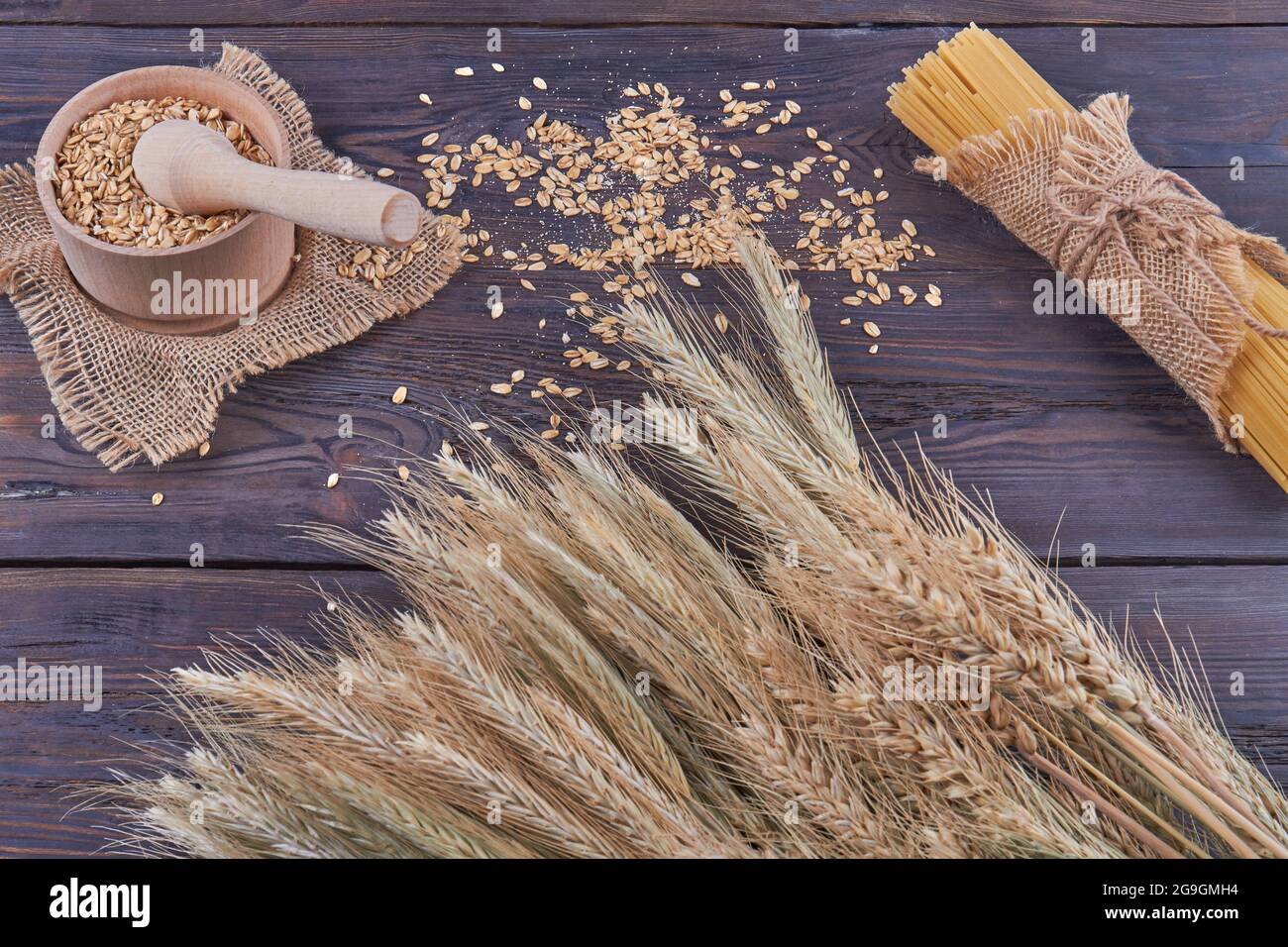 Vue de dessus grains de blé avec moulin à mortier et spaghetti sur bois sombre. Banque D'Images Vue de dessus grains de blé avec moulin à mortier et spaghetti sur bois sombre. Banque D'Images