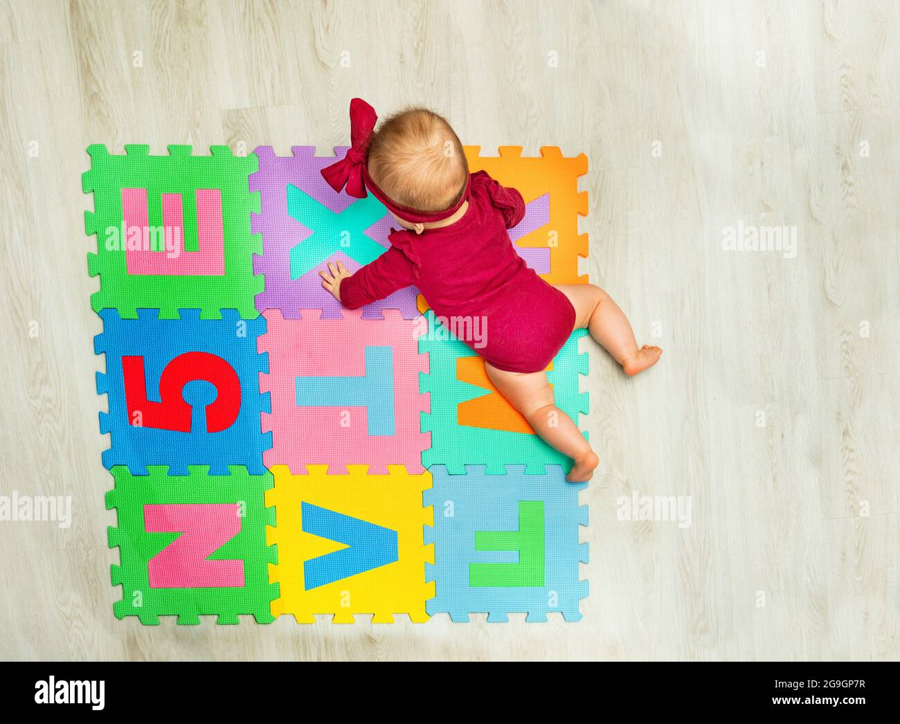 Bonne petite fille fluage sur la moquette avec des lettres Banque D'Images