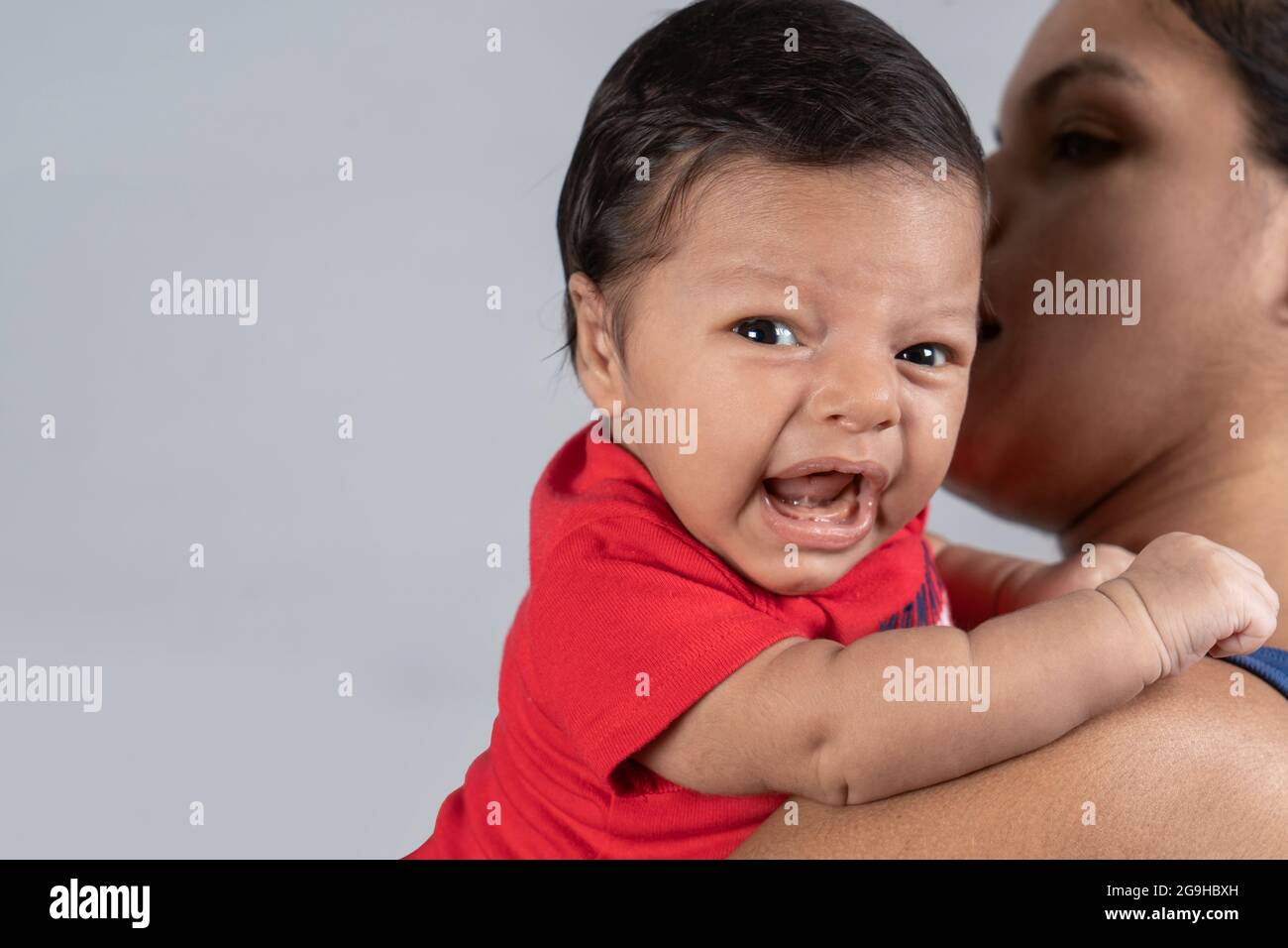 Bébé avec expression de pleurs, porté dans les mains d'une femme Banque D'Images