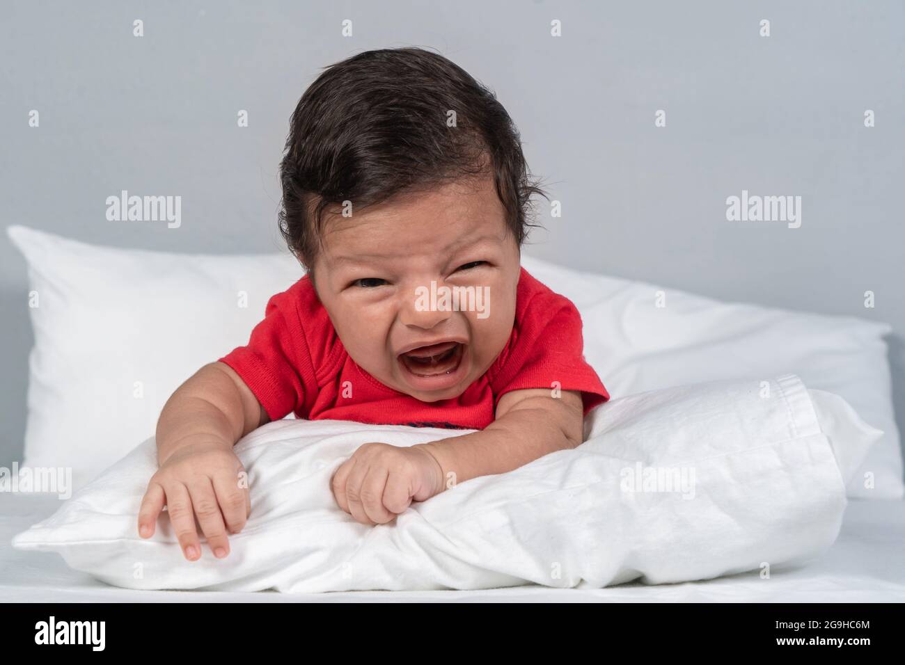 Bébé avec une expression pleurs, allongé sur son ventre avec sa tête  relevée Photo Stock - Alamy