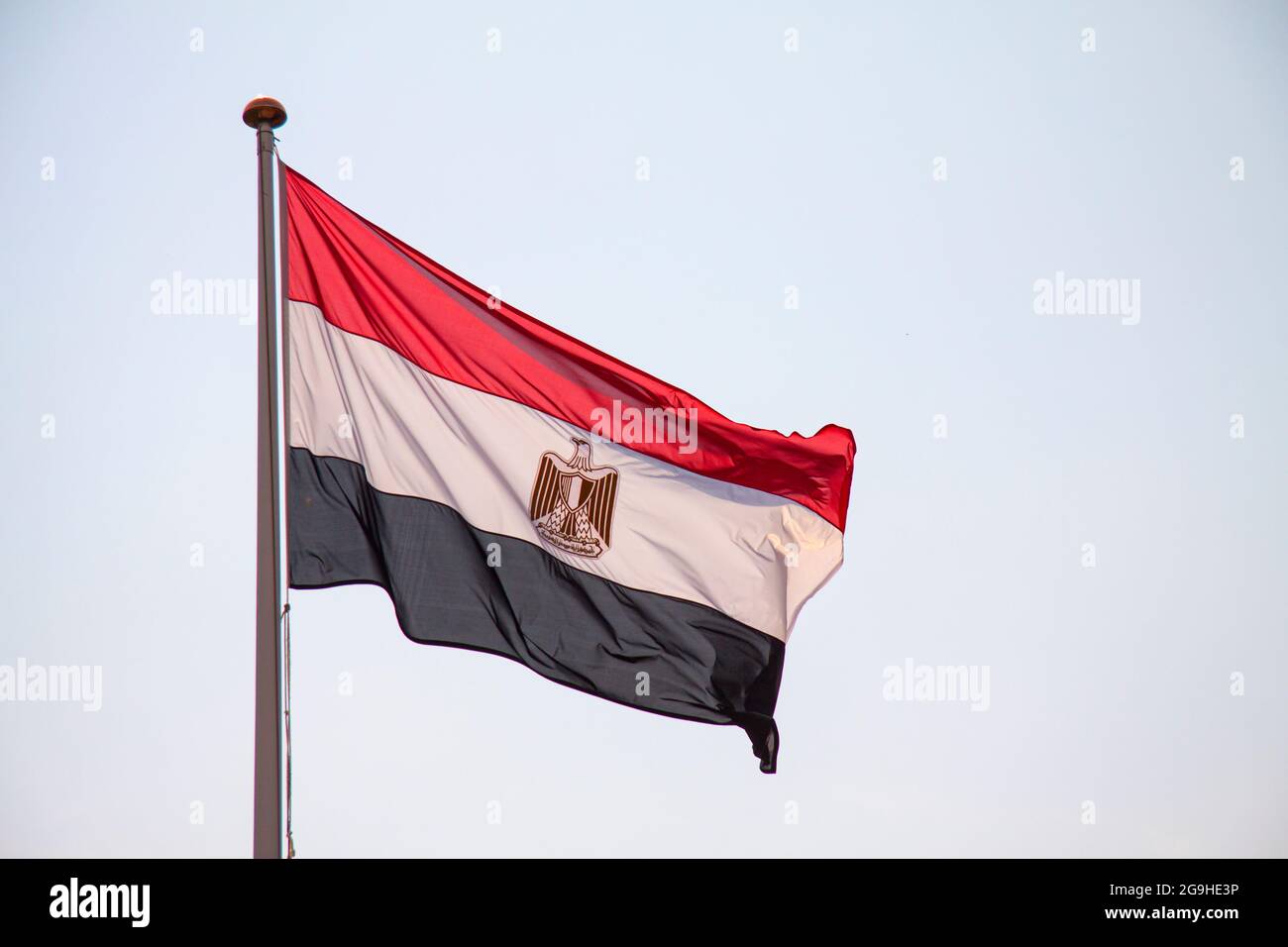 Le drapeau national de l'Égypte agitant dans le vent avec fond bleu ciel. Banque D'Images