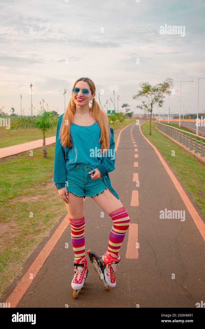 Photo verticale d'une jeune femme hispanique vêque d'une tenue de patinage à roulettes rétro sur un sentier Banque D'Images