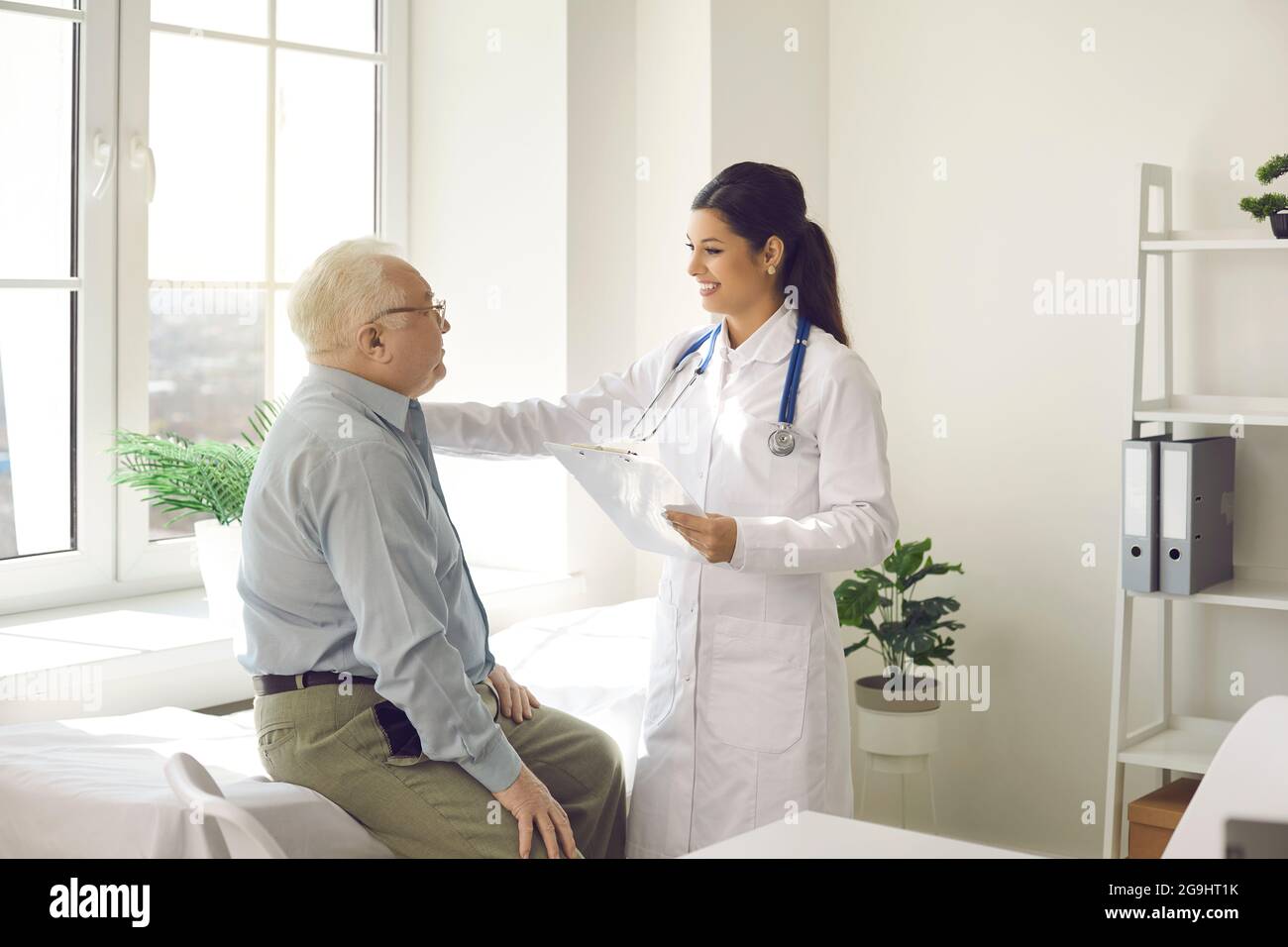 Femme médecin indiquant de bons résultats de traitement à la vieille patiente au bureau de l'hôpital Banque D'Images