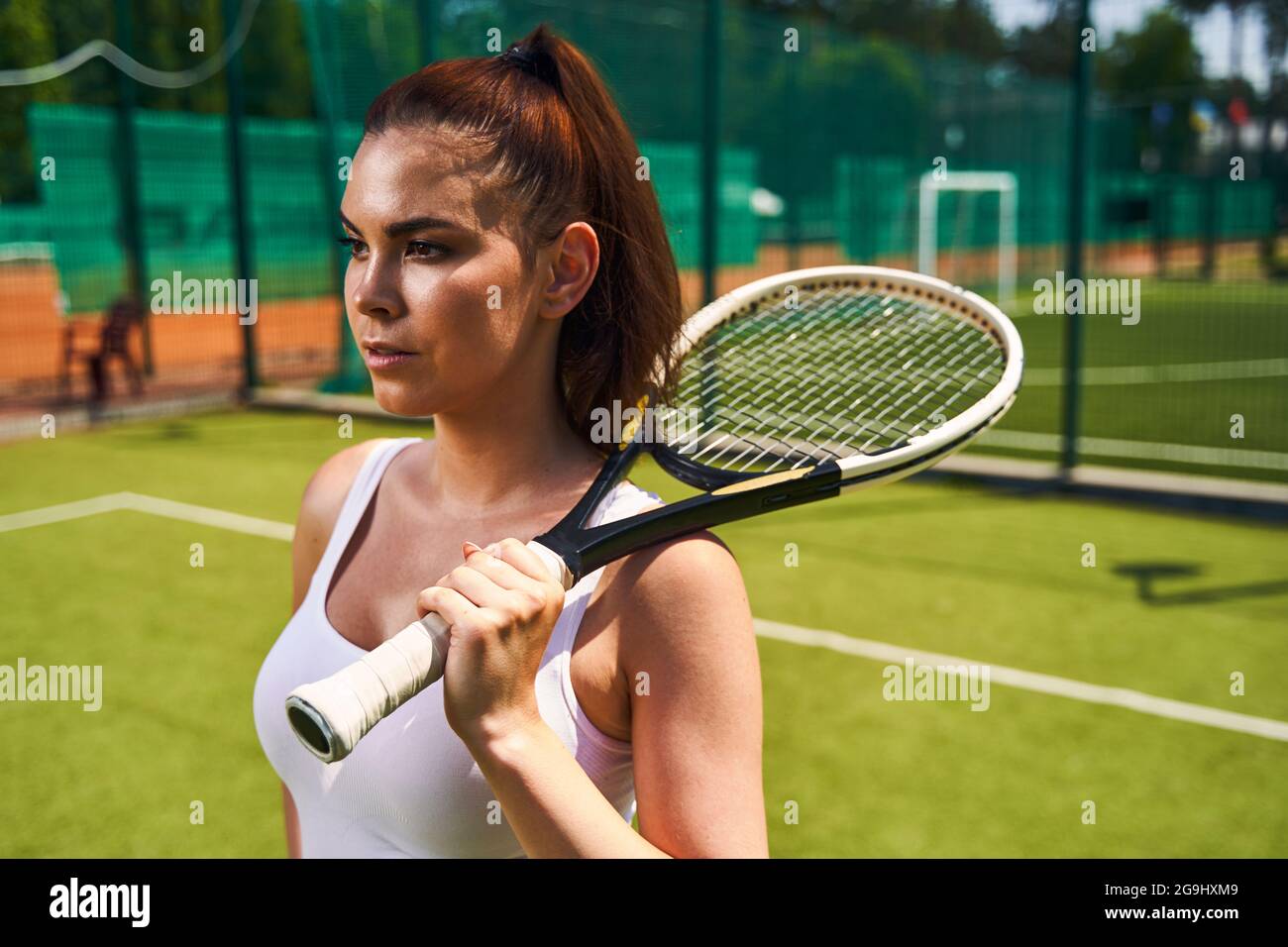 Jeune athlète pensif debout sur le court de tennis Banque D'Images