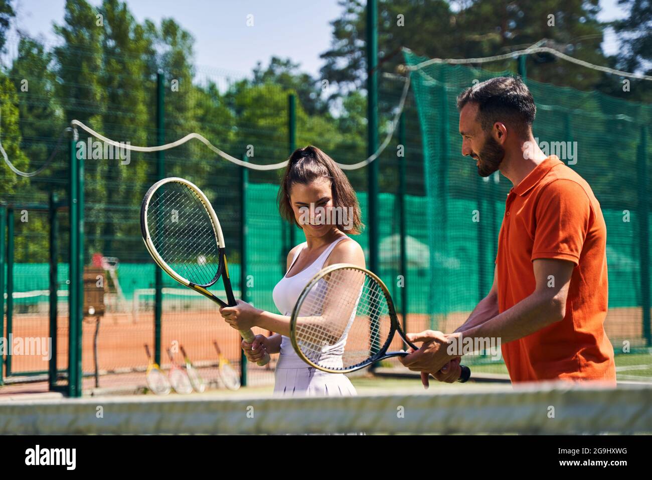 Instructeur montrant une bonne technique de manche de tennis à son client Banque D'Images