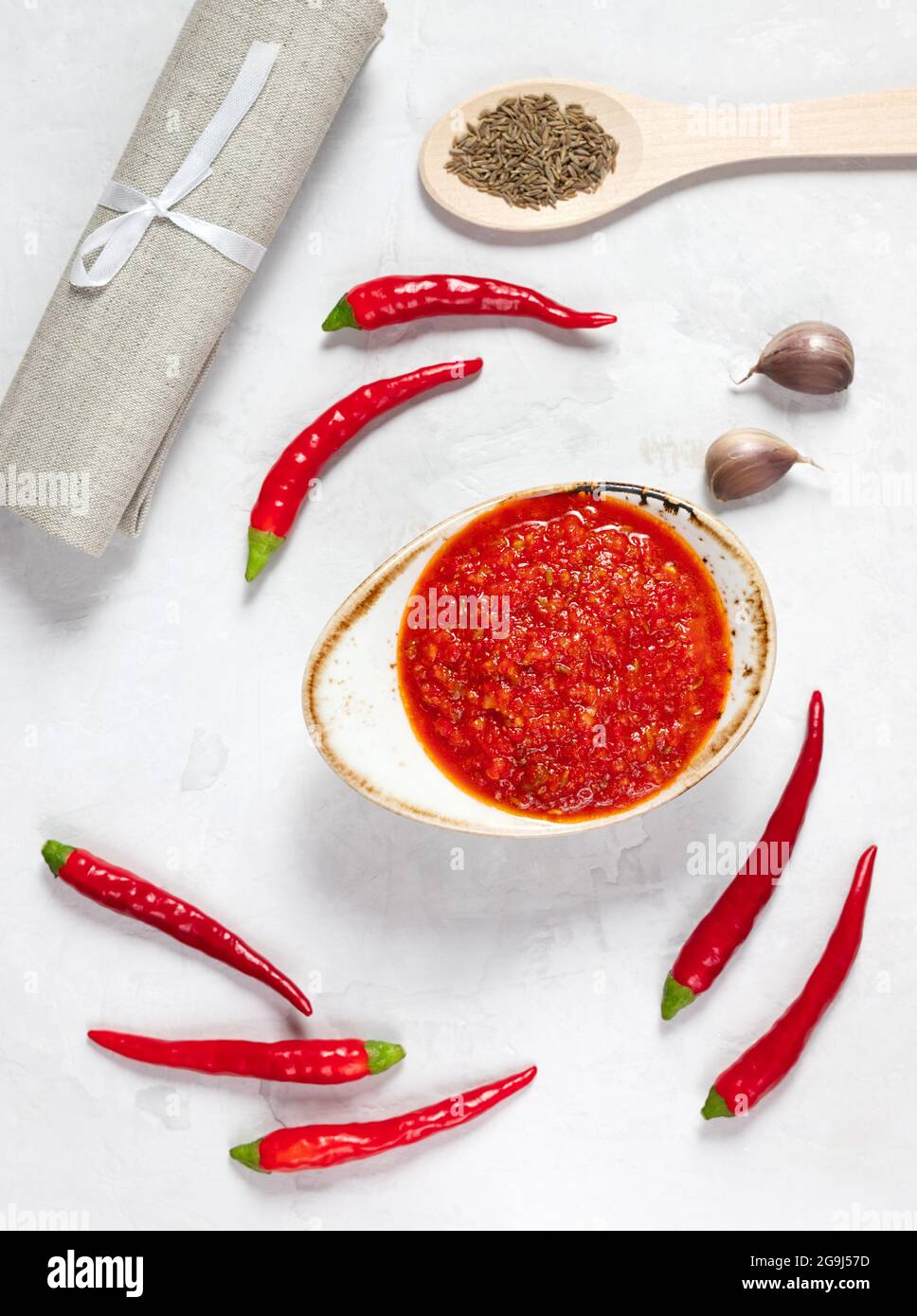 Pâte Harissa. Sauce au piment fort sur fond blanc. Adjika dans un bol avec Chili, ail et épices. Orientation verticale. Vue de dessus. Banque D'Images