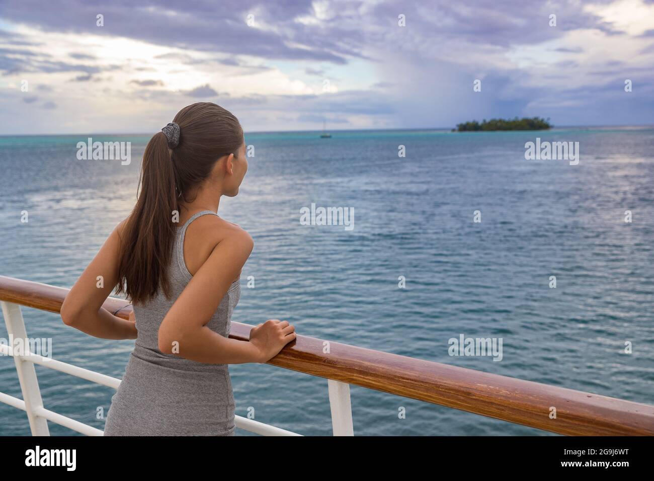 Luxueuse croisière femme de vacances regardant l'île motu de Polynésie française depuis le pont de bateau au coucher du soleil. Détente touristique élégante avec vue sur l'océan à Banque D'Images